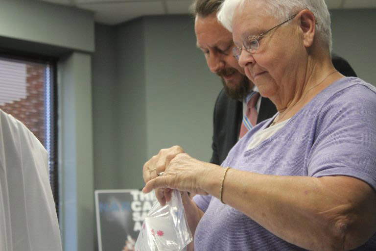 An older woman with a man next to her putting NARCAN into bags.