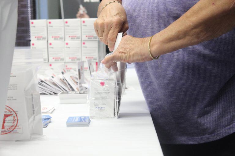 Image of a woman stuffing plastic bags on a table with NARCAN.