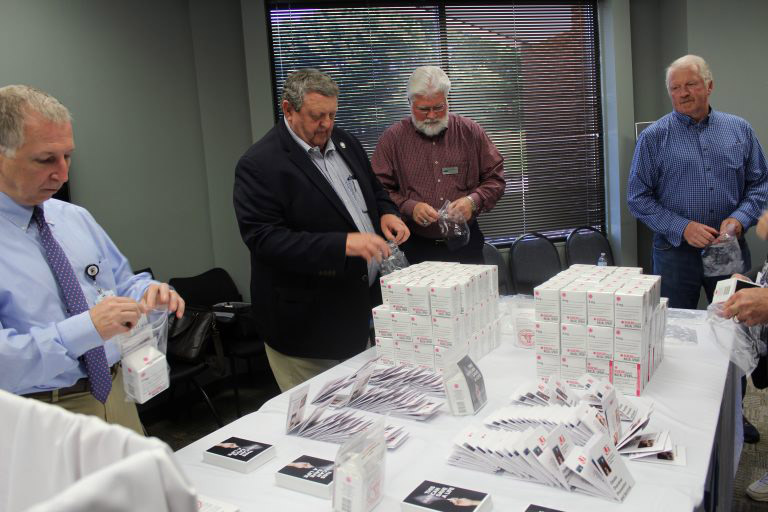 Four men standing around a table displaying NARCAN.