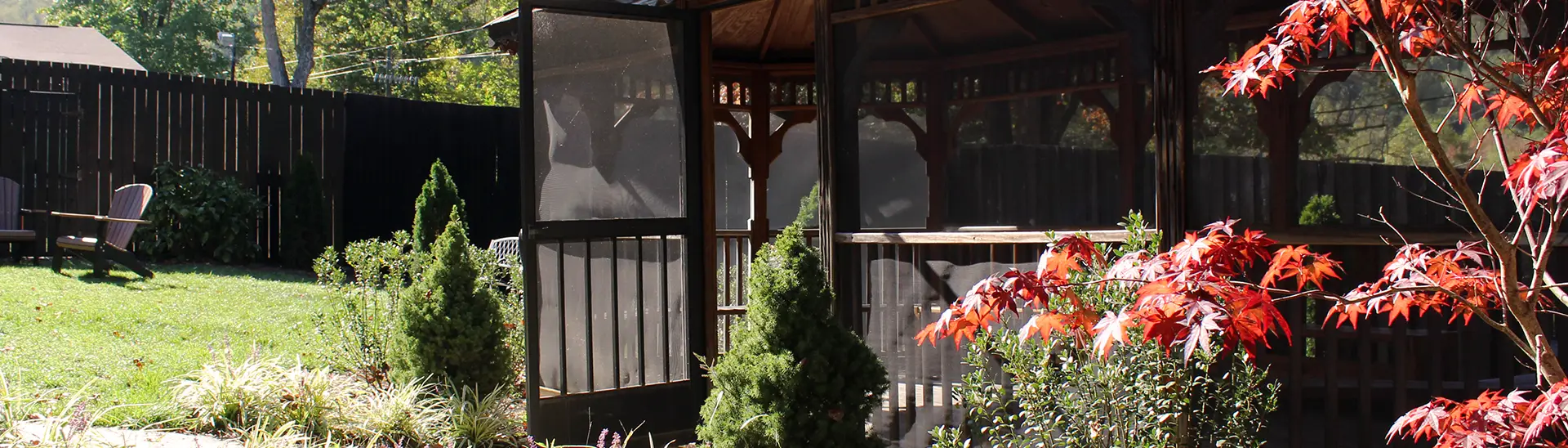 An outside veranda at the Balsam Center with trees and a seating area with Adirondack chairs.