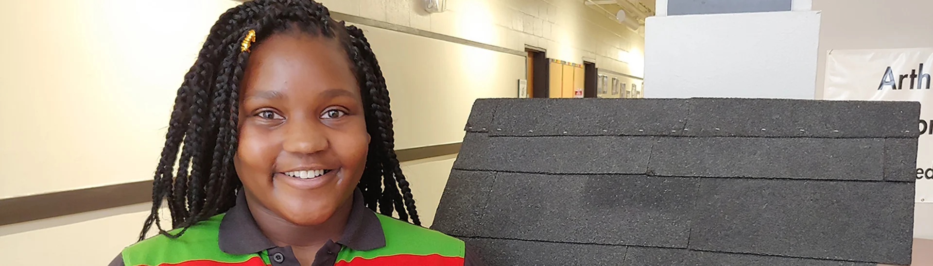 Hadyyah Williams an African American woman stands smiling next to a roof display.