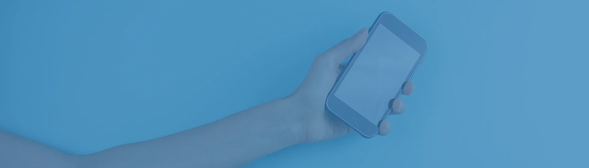 Brazo extendido sosteniendo un teléfono en la mano con un filtro azul sobre toda la imagen.