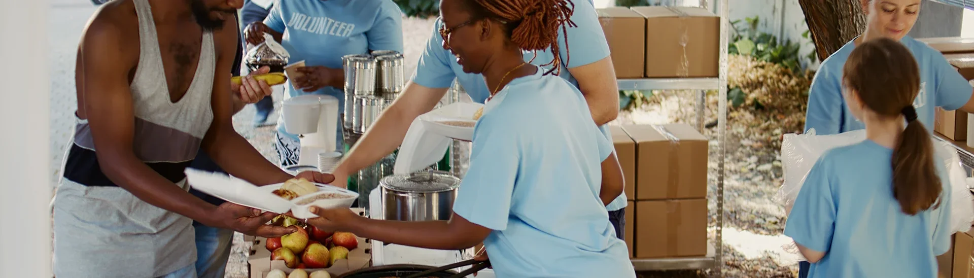 A man is being provided food by volunteers to help feed the homeless.