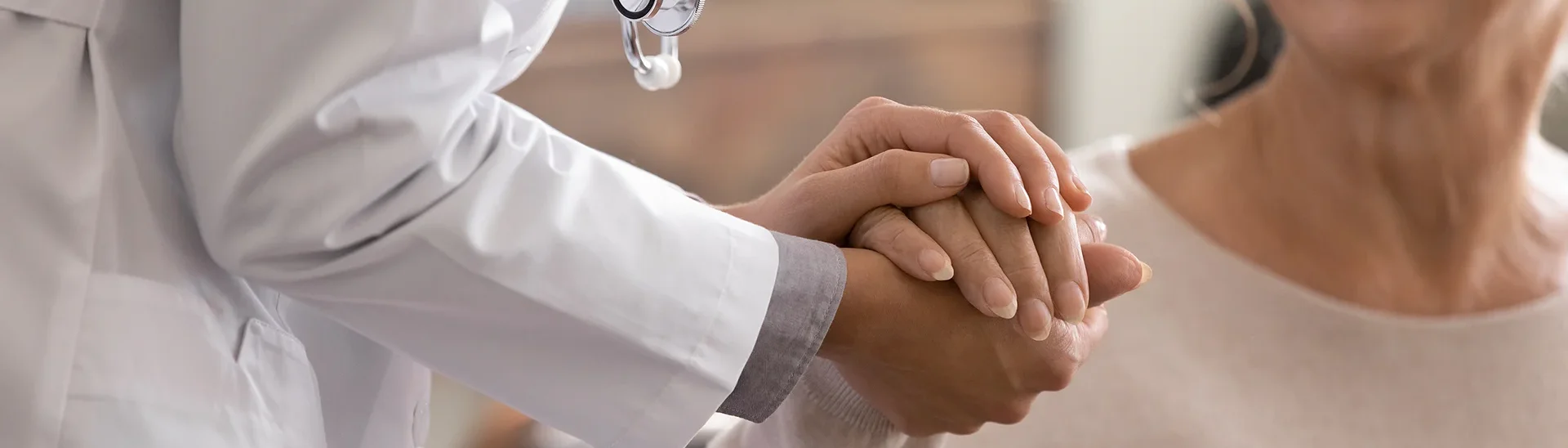 A doctor giving a supportive handshake to an elderly woman.