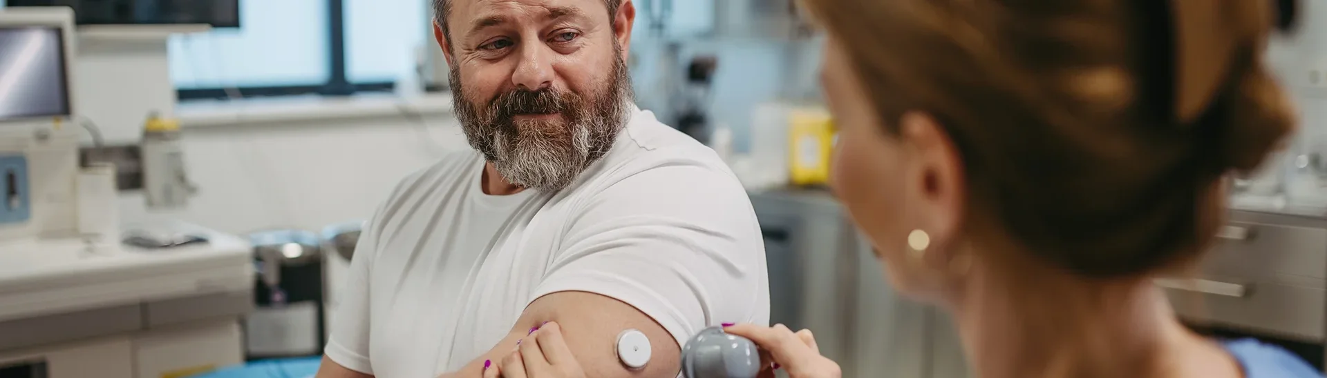 Man putting on a blood sugar monitor onto his arm to manage his diabetes.