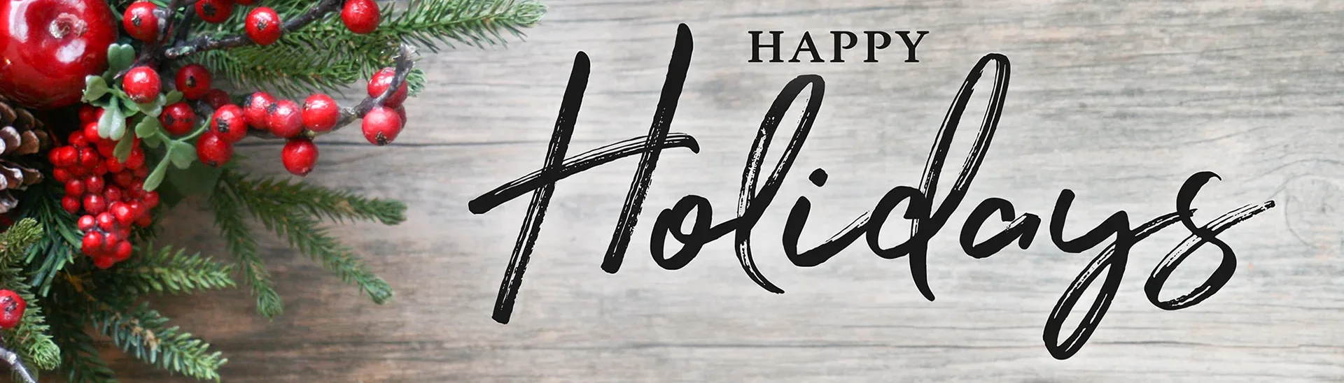 Happy holidays sign with holly berries to the left of the photo with a grey background.