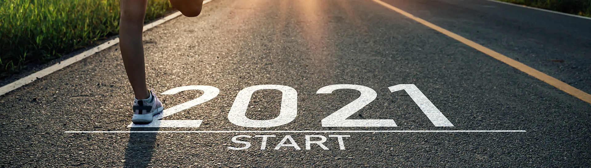 A person jogging down the road with tall grass on either side. On the road is written 2021.