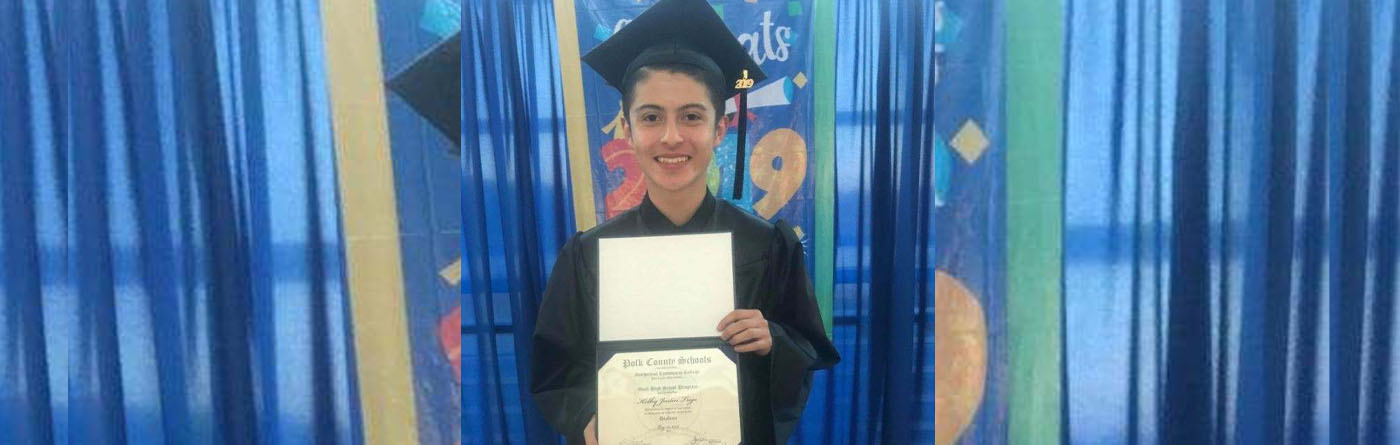 Young boy who graduated from high school holding his diploma.