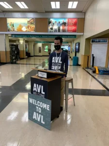 Vaya volunteer at Asheville regional airport greeting guests as they arrive near the baggage claim.