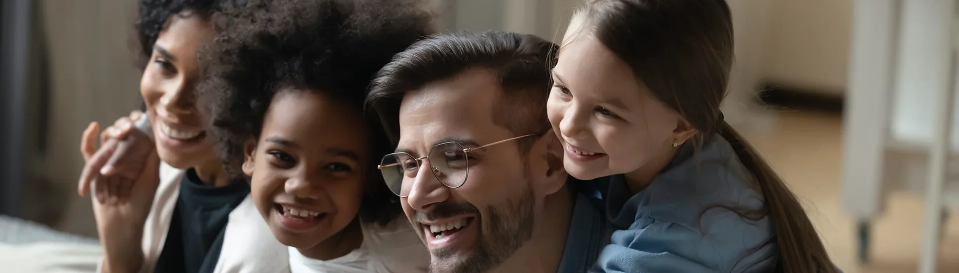 Multicultural family sitting arm to arm smiling together.