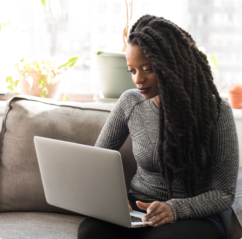 a person sitting on a gray couch working on a laptop