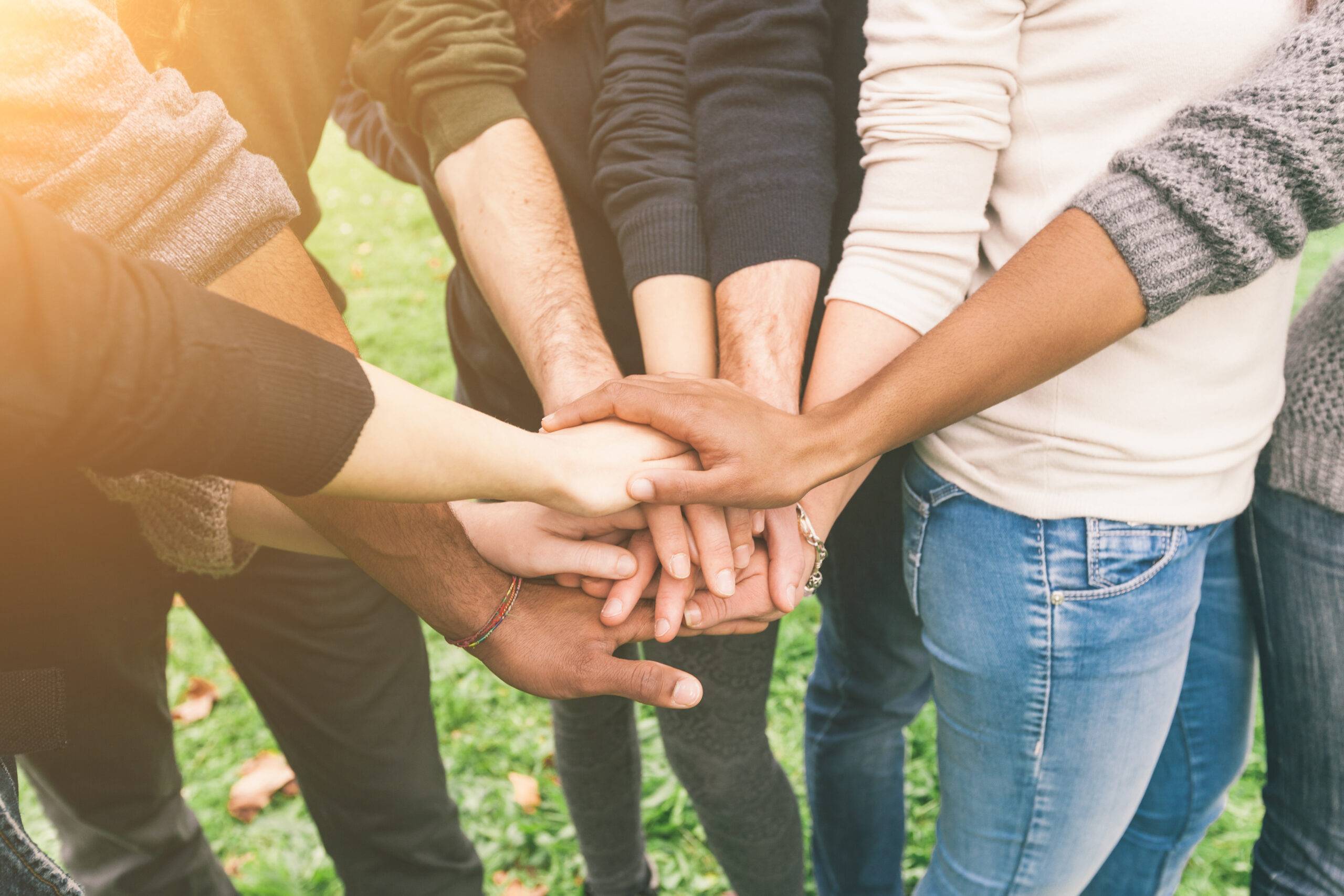 Multiracial,Group,Of,Friends,With,Hands,In,Stack,,Teamwork