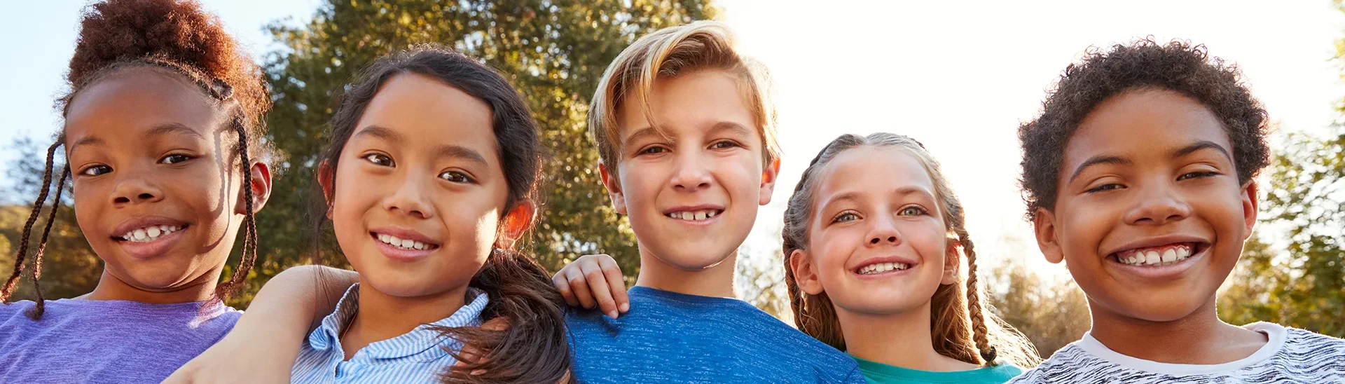 Diverse group of young children smiling together outside