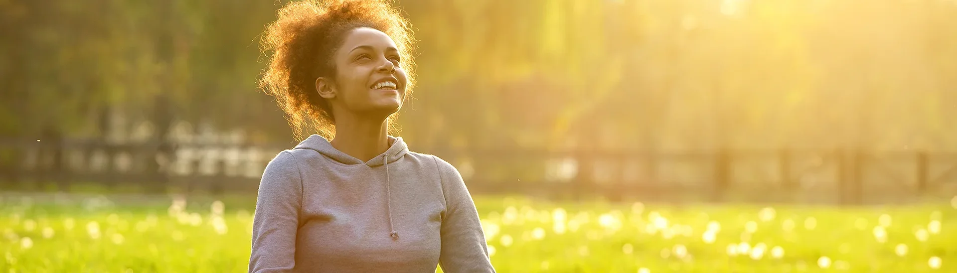 Joven afroamericana sentada en un campo con el sol brillando