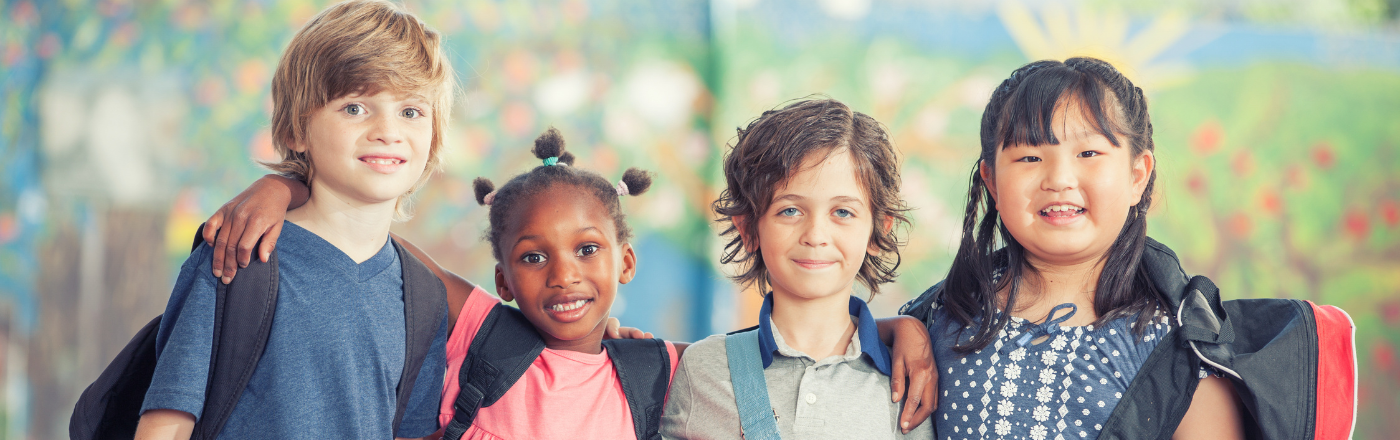 Diverse group of children smiling together at school