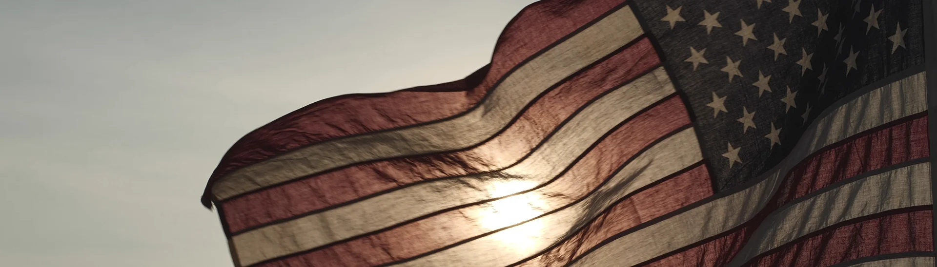 The American flag blowing in the wind at sunset.