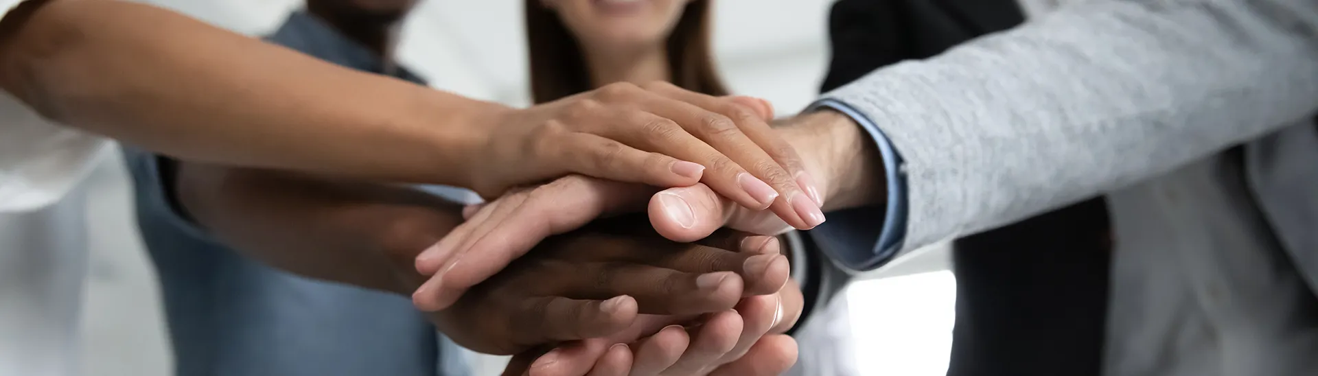 A group of diverse people putting their hands together, on top of each ones in support for care.