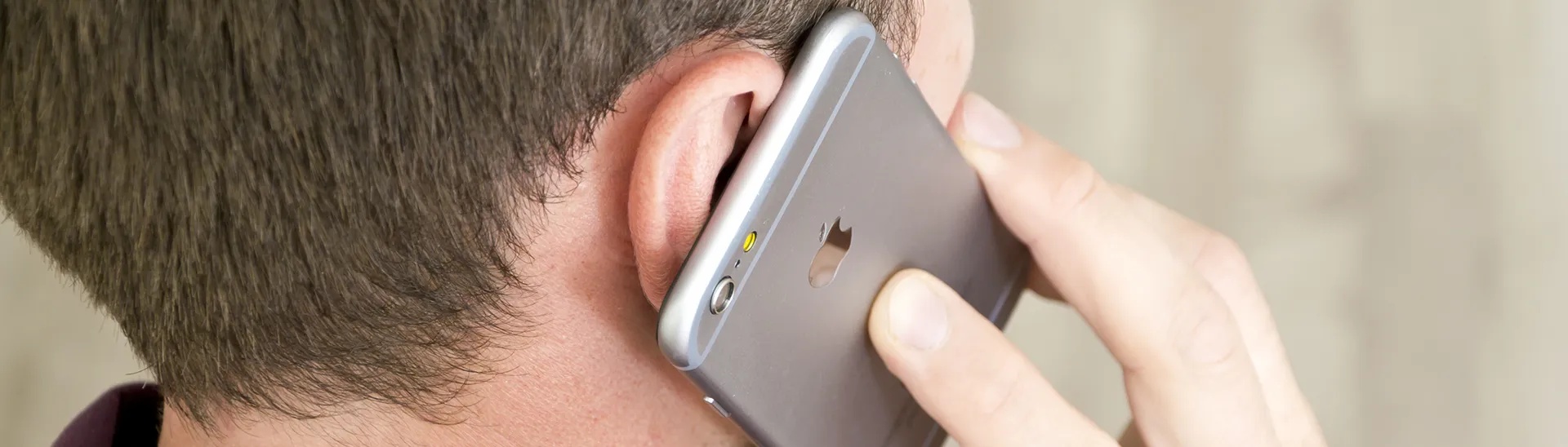 A man talking with a phone to his ear talking to someone for help.