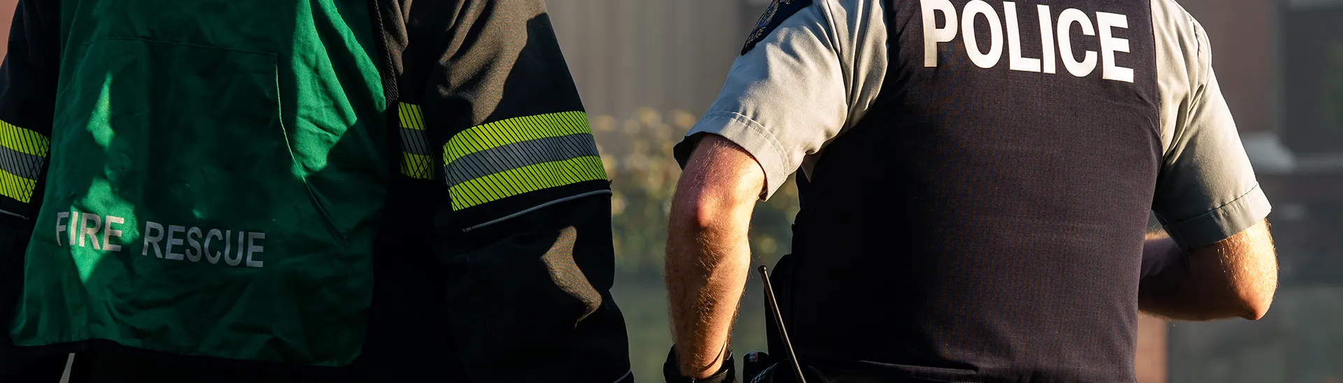 A police officer and a firefighter standing next to each other in front of a building.