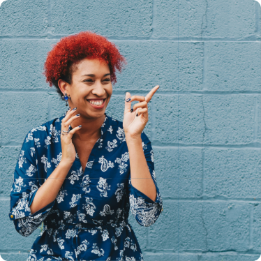 girl-red-hair-smiling Girl with red hair and blue dress smiling with a blue brick wall behind her.