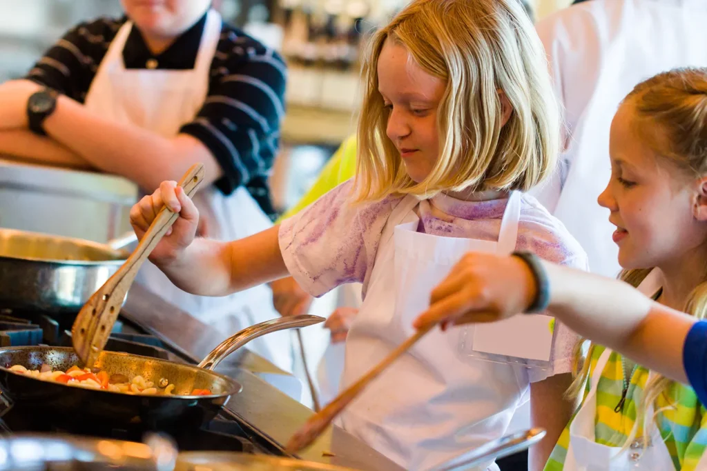 Niños aprendiendo a cocinar durante una actividad del programa WNC Thrive.