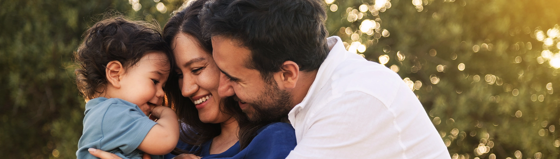 A mother and father holding their little child happily smiling together