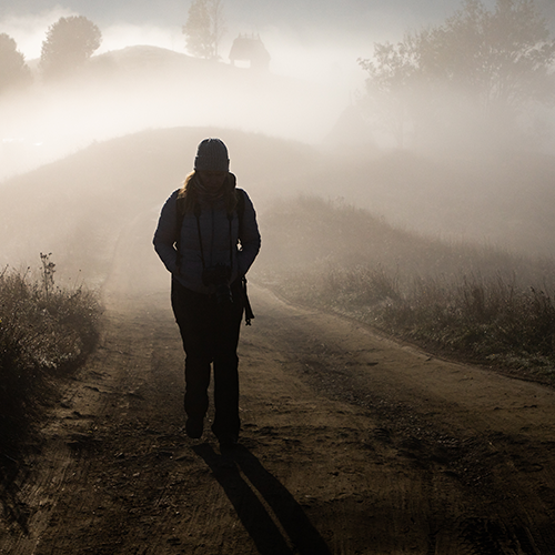 PTSD_Awareness_banner_500x500_20260527 PTSD Awareness image of a woman walking down a foggy road alone.